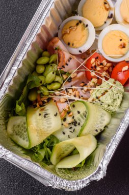 Kaynamış yumurta, jambon, domates, yeşil fasulye, koyu beton arkaplanda aioli sosu içeren sağlıklı bir kahvaltı.