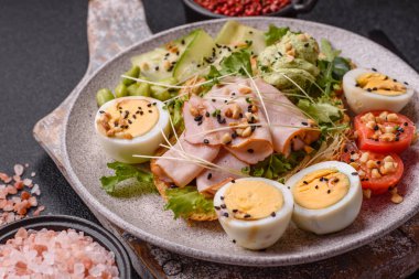 Kaynamış yumurta, jambon, domates, yeşil fasulye, koyu beton arkaplanda aioli sosu içeren sağlıklı bir kahvaltı.