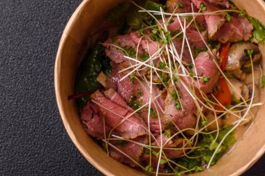 Biftek, yeşillik, domates, salatalık, koyu beton arkaplanda yeşil fasulye dilimlerinden oluşan ılık salata.