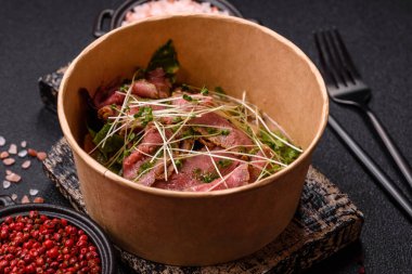 Biftek, yeşillik, domates, salatalık, koyu beton arkaplanda yeşil fasulye dilimlerinden oluşan ılık salata.