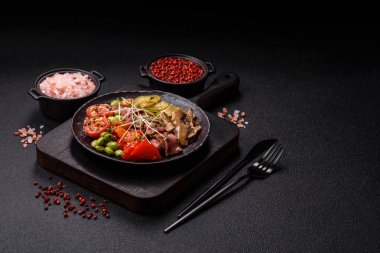 Biftek, yeşillik, domates, salatalık, koyu beton arkaplanda yeşil fasulye dilimlerinden oluşan ılık salata.