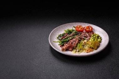 Biftek, yeşillik, domates, salatalık, koyu beton arkaplanda yeşil fasulye dilimlerinden oluşan ılık salata.