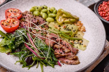 Biftek, yeşillik, domates, salatalık, koyu beton arkaplanda yeşil fasulye dilimlerinden oluşan ılık salata.