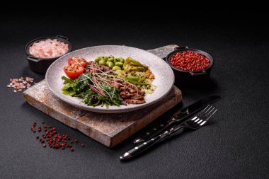 Biftek, yeşillik, domates, salatalık, koyu beton arkaplanda yeşil fasulye dilimlerinden oluşan ılık salata.