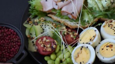 Kaynamış yumurta, jambon, domates, yeşil fasulye, koyu beton arkaplanda aioli sosu içeren sağlıklı bir kahvaltı.