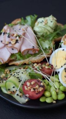 Kaynamış yumurta, jambon, domates, yeşil fasulye, koyu beton arkaplanda aioli sosu içeren sağlıklı bir kahvaltı.