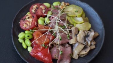 Biftek, yeşillik, domates, salatalık, koyu beton arkaplanda yeşil fasulye dilimlerinden oluşan ılık salata.