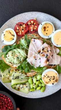 Kaynamış yumurta, jambon, domates, yeşil fasulye, koyu beton arkaplanda aioli sosu içeren sağlıklı bir kahvaltı.