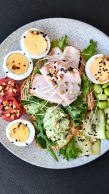 Kaynamış yumurta, jambon, domates, yeşil fasulye, koyu beton arkaplanda aioli sosu içeren sağlıklı bir kahvaltı.