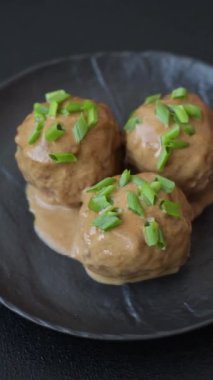 Koyu beton arkaplanda kremalı karamel soslu tuz ve baharatlı köfteler.