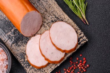 Delicious fresh ham cut into round slices with salt, spices and herbs on a dark concrete background clipart