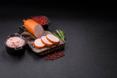 Lezzetli taze jambon, tuz, baharat ve otlarla kesilmiş koyu beton arka planda yuvarlak dilimler halinde.