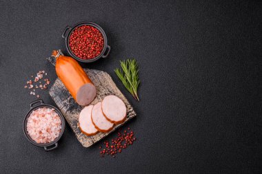 Lezzetli taze jambon, tuz, baharat ve otlarla kesilmiş koyu beton arka planda yuvarlak dilimler halinde.