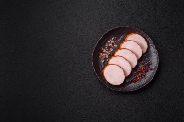 Lezzetli taze jambon, tuz, baharat ve otlarla kesilmiş koyu beton arka planda yuvarlak dilimler halinde.