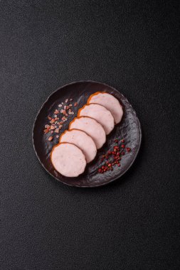 Lezzetli taze jambon, tuz, baharat ve otlarla kesilmiş koyu beton arka planda yuvarlak dilimler halinde.