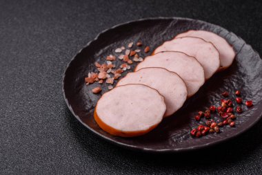 Lezzetli taze jambon, tuz, baharat ve otlarla kesilmiş koyu beton arka planda yuvarlak dilimler halinde.