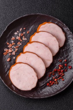 Lezzetli taze jambon, tuz, baharat ve otlarla kesilmiş koyu beton arka planda yuvarlak dilimler halinde.