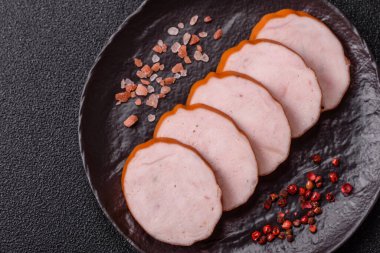 Lezzetli taze jambon, tuz, baharat ve otlarla kesilmiş koyu beton arka planda yuvarlak dilimler halinde.