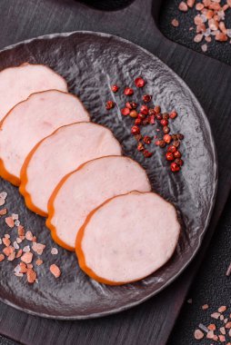 Lezzetli taze jambon, tuz, baharat ve otlarla kesilmiş koyu beton arka planda yuvarlak dilimler halinde.