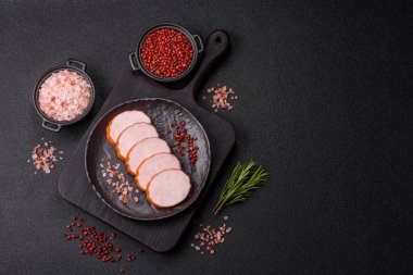 Lezzetli taze jambon, tuz, baharat ve otlarla kesilmiş koyu beton arka planda yuvarlak dilimler halinde.