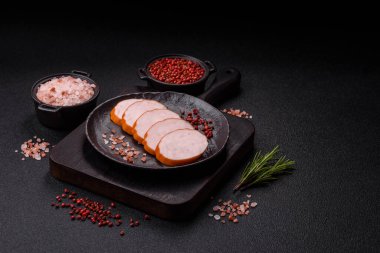 Lezzetli taze jambon, tuz, baharat ve otlarla kesilmiş koyu beton arka planda yuvarlak dilimler halinde.