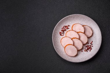 Lezzetli taze jambon, tuz, baharat ve otlarla kesilmiş koyu beton arka planda yuvarlak dilimler halinde.