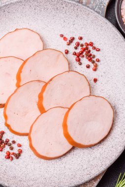 Lezzetli taze jambon, tuz, baharat ve otlarla kesilmiş koyu beton arka planda yuvarlak dilimler halinde.