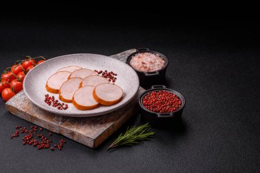 Lezzetli taze jambon, tuz, baharat ve otlarla kesilmiş koyu beton arka planda yuvarlak dilimler halinde.