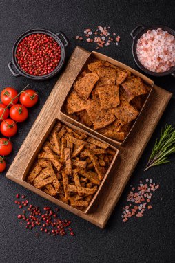 Koyu beton arka planda tohum ve tahıllı, tuzlu, baharatlı ve otlu ev yapımı kahverengi ekmek krakerleri veya kızarmış ekmekler.