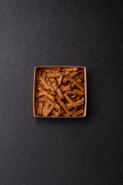 Koyu beton arka planda tohum ve tahıllı, tuzlu, baharatlı ve otlu ev yapımı kahverengi ekmek krakerleri veya kızarmış ekmekler.