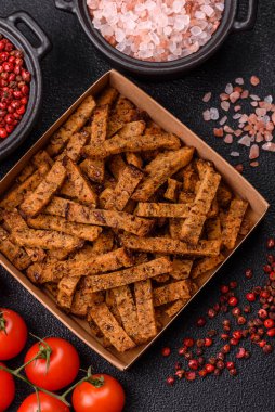 Koyu beton arka planda tohum ve tahıllı, tuzlu, baharatlı ve otlu ev yapımı kahverengi ekmek krakerleri veya kızarmış ekmekler.