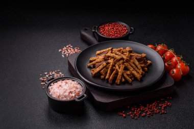 Koyu beton arka planda tohum ve tahıllı, tuzlu, baharatlı ve otlu ev yapımı kahverengi ekmek krakerleri veya kızarmış ekmekler.