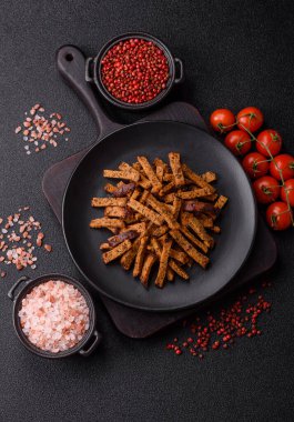 Koyu beton arka planda tohum ve tahıllı, tuzlu, baharatlı ve otlu ev yapımı kahverengi ekmek krakerleri veya kızarmış ekmekler.