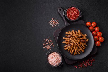 Koyu beton arka planda tohum ve tahıllı, tuzlu, baharatlı ve otlu ev yapımı kahverengi ekmek krakerleri veya kızarmış ekmekler.