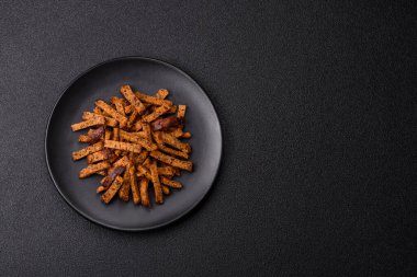 Koyu beton arka planda tohum ve tahıllı, tuzlu, baharatlı ve otlu ev yapımı kahverengi ekmek krakerleri veya kızarmış ekmekler.