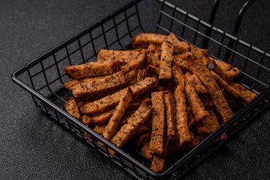 Koyu beton arka planda tohum ve tahıllı, tuzlu, baharatlı ve otlu ev yapımı kahverengi ekmek krakerleri veya kızarmış ekmekler.