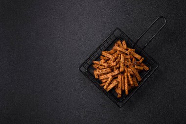 Koyu beton arka planda tohum ve tahıllı, tuzlu, baharatlı ve otlu ev yapımı kahverengi ekmek krakerleri veya kızarmış ekmekler.