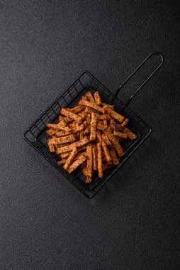 Koyu beton arka planda tohum ve tahıllı, tuzlu, baharatlı ve otlu ev yapımı kahverengi ekmek krakerleri veya kızarmış ekmekler.