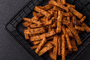 Koyu beton arka planda tohum ve tahıllı, tuzlu, baharatlı ve otlu ev yapımı kahverengi ekmek krakerleri veya kızarmış ekmekler.