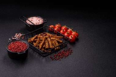 Koyu beton arka planda tohum ve tahıllı, tuzlu, baharatlı ve otlu ev yapımı kahverengi ekmek krakerleri veya kızarmış ekmekler.