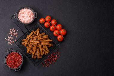 Koyu beton arka planda tohum ve tahıllı, tuzlu, baharatlı ve otlu ev yapımı kahverengi ekmek krakerleri veya kızarmış ekmekler.