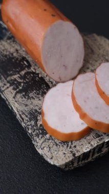 Lezzetli taze jambon, tuz, baharat ve otlarla kesilmiş koyu beton arka planda yuvarlak dilimler halinde.