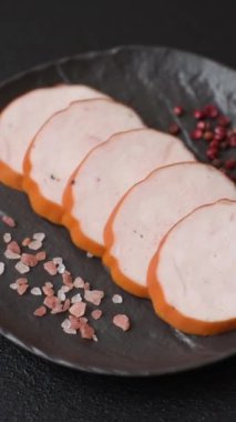 Lezzetli taze jambon, tuz, baharat ve otlarla kesilmiş koyu beton arka planda yuvarlak dilimler halinde.