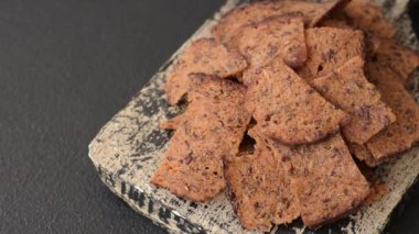 Tohumlar, tanecikler, tuz, baharatlar ve çimento kaplı ev yapımı çıtır kahverengi ekmek cipsleri.