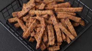 Koyu beton arka planda tohum ve tahıllı, tuzlu, baharatlı ve otlu ev yapımı kahverengi ekmek krakerleri veya kızarmış ekmekler.