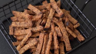 Koyu beton arka planda tohum ve tahıllı, tuzlu, baharatlı ve otlu ev yapımı kahverengi ekmek krakerleri veya kızarmış ekmekler.