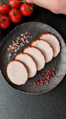 Lezzetli taze jambon, tuz, baharat ve otlarla kesilmiş koyu beton arka planda yuvarlak dilimler halinde.