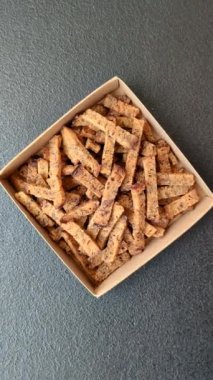 Koyu beton arka planda tohum ve tahıllı, tuzlu, baharatlı ve otlu ev yapımı kahverengi ekmek krakerleri veya kızarmış ekmekler.