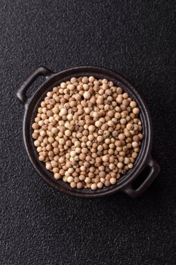 Koyu beton arka planda seramik bir kasede tüm baharatlar beyaz.