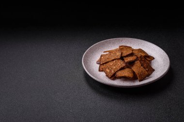 Tohumlar, tanecikler, tuz, baharatlar ve çimento kaplı ev yapımı çıtır kahverengi ekmek cipsleri.